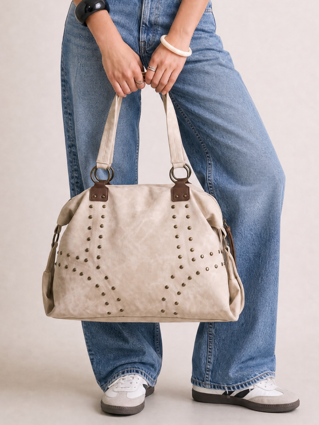 Model holding the Le Solene white studded shoulder bag by the handle