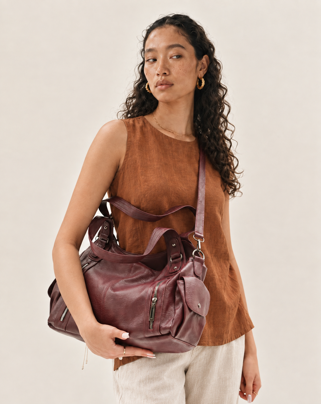 Model holding the L'Elyn burgundy vegan leather bag, front view