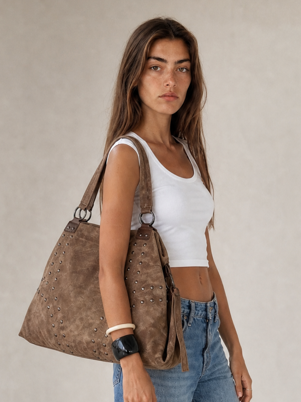 Model wearing the Le Solene coffee studded shoulder bag, front view