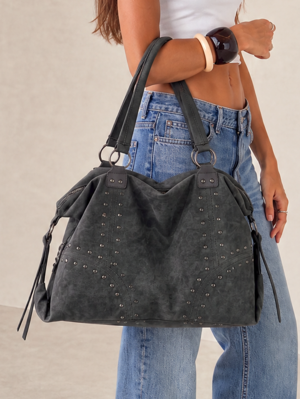 Close-up of a model wearing the Le Solene black studded shoulder bag