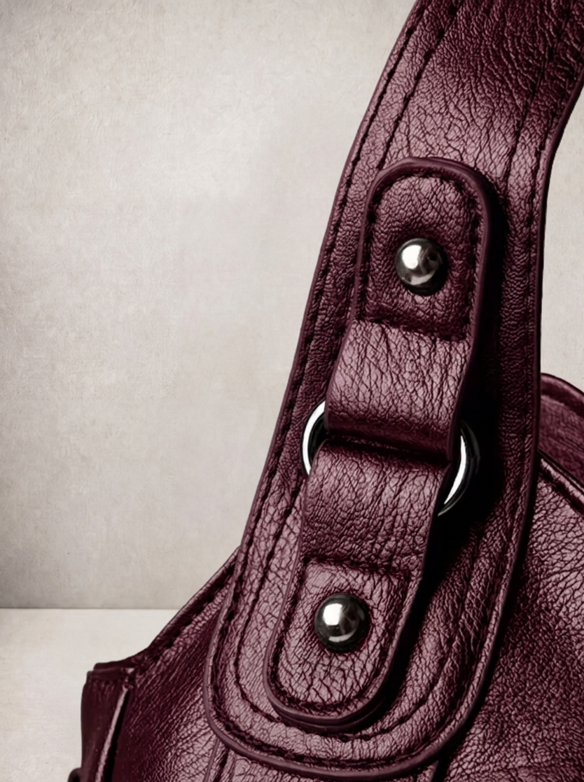 Close-up of the stud and rivet hardware on the L'Elyn burgundy bag