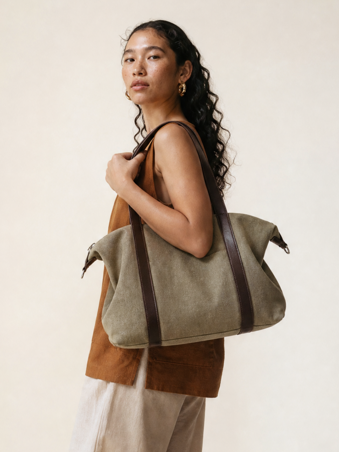Model wearing the Le Meline green canvas tote bag on her shoulder with brown leather straps