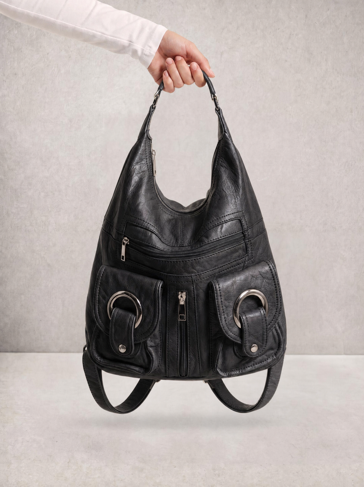 Close-up of a hand holding the Le Mila black bag by its top handle