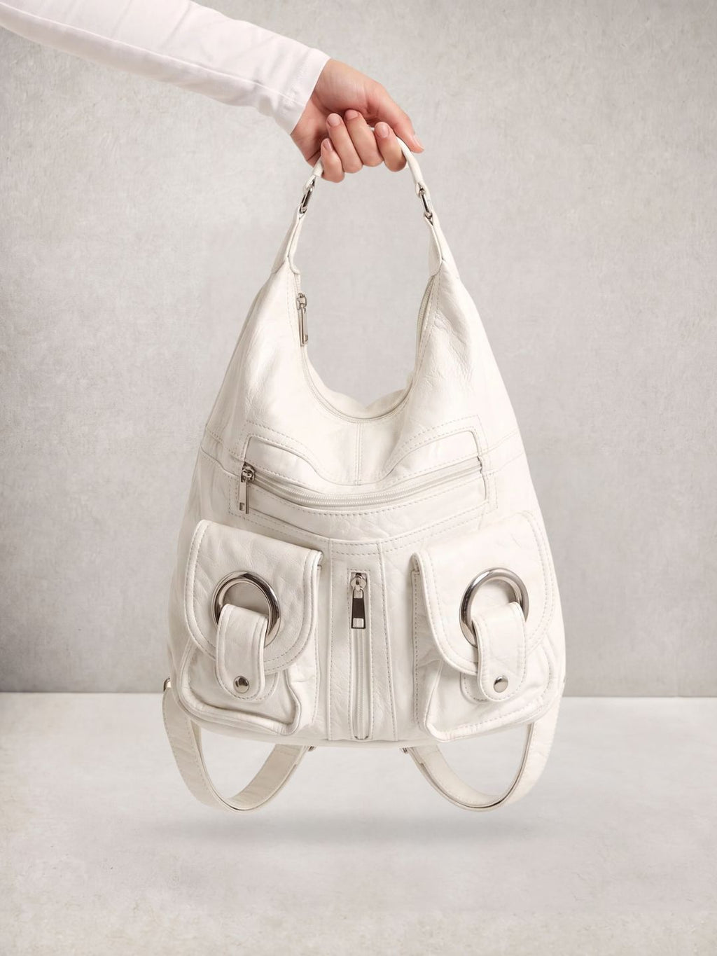 Close-up of a hand holding the Le Mila white bag by its top handle