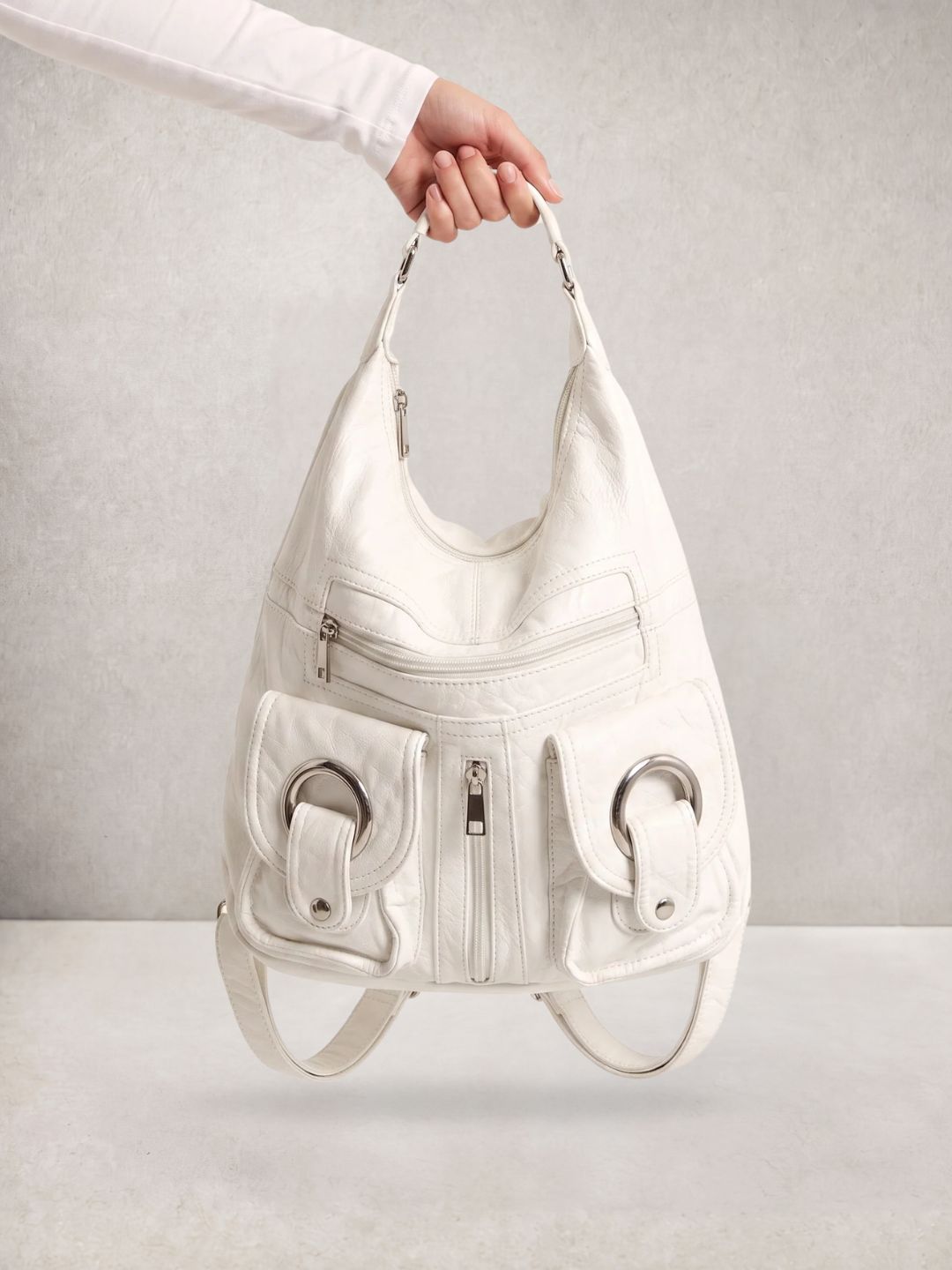 Close-up of a hand holding the Le Mila white bag by its top handle