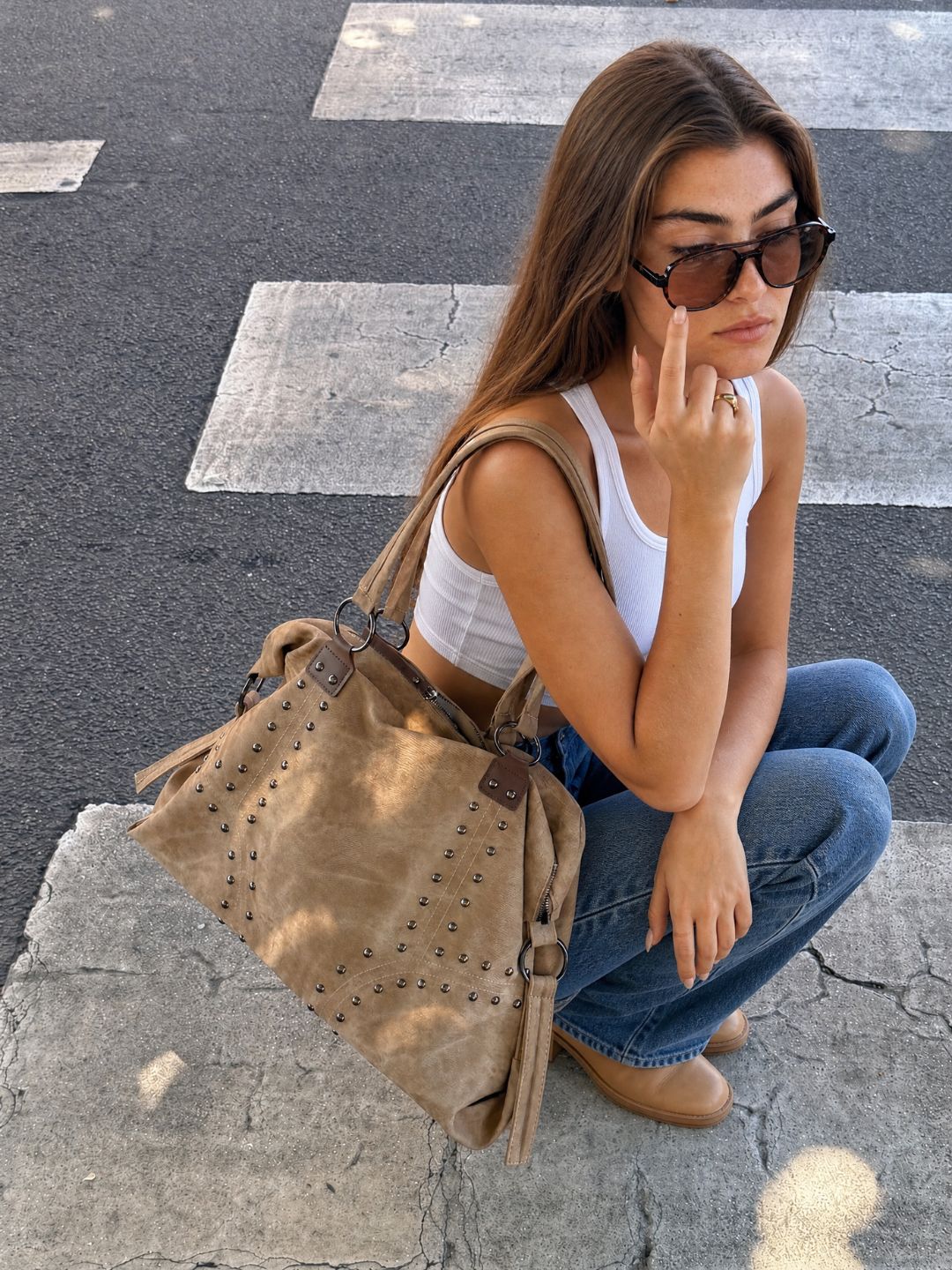 Model sitting outdoors wearing sunglasses, carrying the Le Solene beige shoulder bag