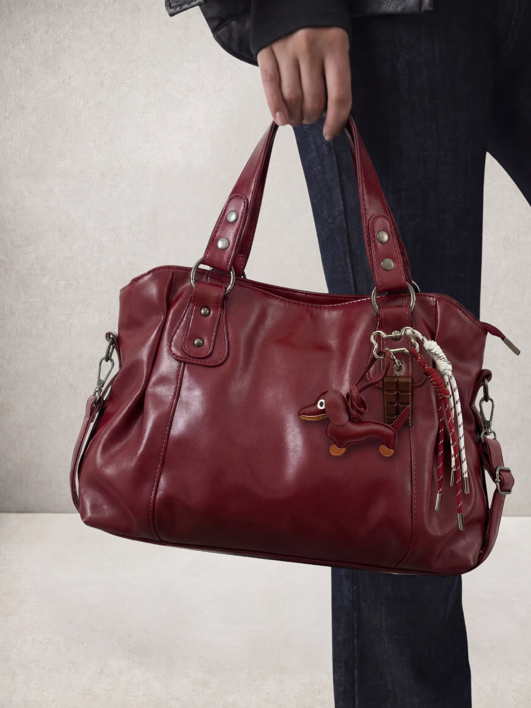 Model holding the Le Sienne burgundy bag by its top handle