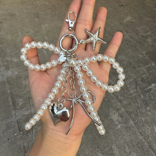 Close-up of a hand holding the Pearl Bow Charm keychain